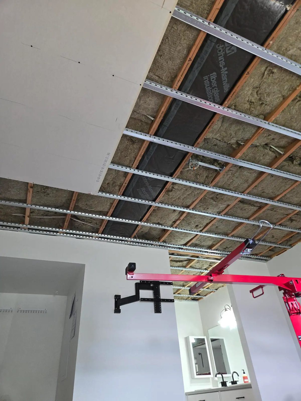 Drywall ceiling installation over resilient channels and acoustic insulation