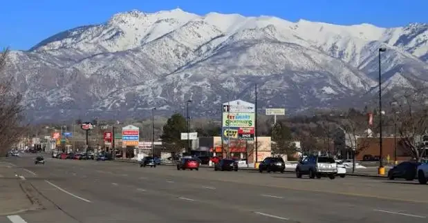 Busy commercial street in Roy, Utah with snow-capped mountains in the background